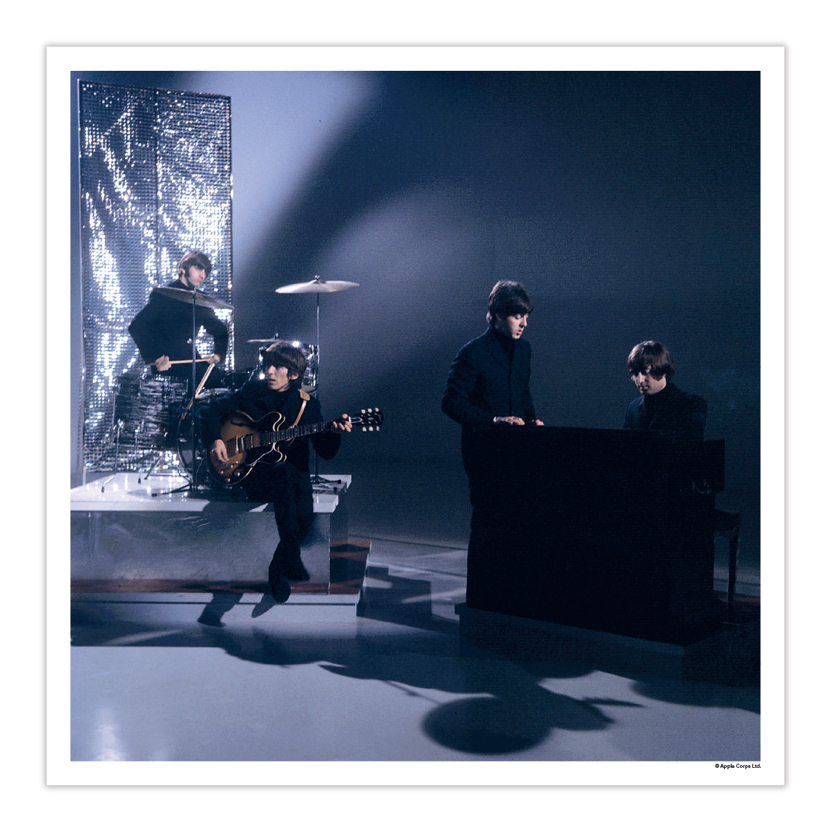 A square art print featuring a black-and-white photograph of the band The Beatles performing live on stage, with dramatic spotlighting and a dark, moody background. The print is framed with a white border. As part of the 5LP Box Set Exclusive